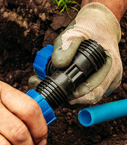 Irrigation System Repair technician holding connectors to sprinkler pipe