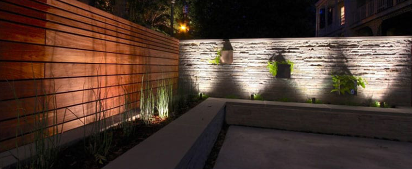 Landscape Lighting fixtures shining up on a wood wall and a stone wall